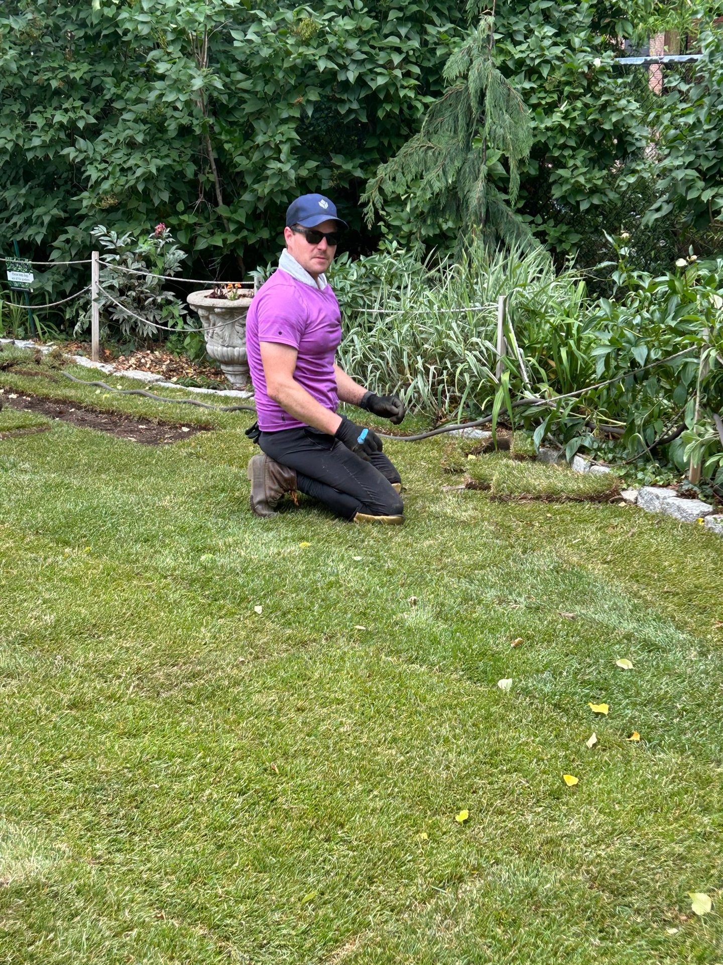 A volunteer kneeling to work on the edge of a finished lawn
