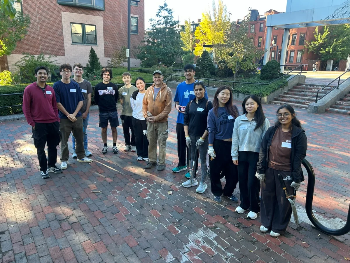 A group with gloves and hand tools stands on a brick plaza